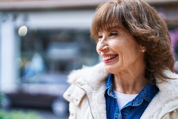 Middle age woman smiling confident looking to the side at street