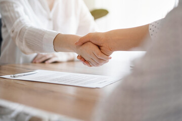 Business people shaking hands above contract papers just signed on the wooden table, close up. Lawyers at meeting. Teamwork, partnership, success concept - 662375060