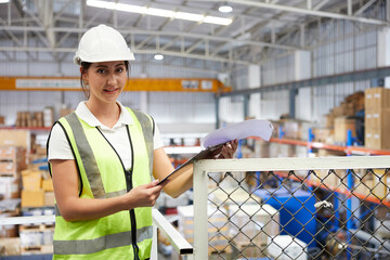 factory worker smiling and holding a clipboard in warehouse storage