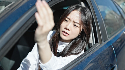 Fototapeta na wymiar Young chinese woman stressed driving car at street