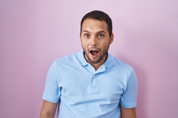 Obraz premium Hispanic man standing over pink background afraid and shocked with surprise and amazed expression, fear and excited face.