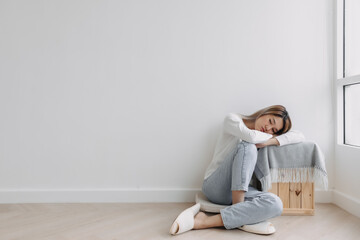 Asian Thai woman sitting on floor and resting head on arms lying on table, feeling sad and worried, thinking something lonely, absent-minded at apartment in winter. 