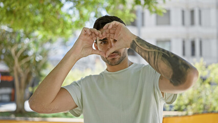 Obraz premium Young hispanic man doing heart gesture with hands at park
