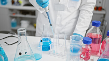 Passionate young hispanic man, an attractive grey-haired scientist, pouring liquid meticulously...
