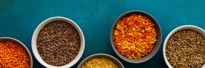 Multicolored lentils in bowls banner, yellow and brown, green and orange lentils, healthy legumes, top view, copy space