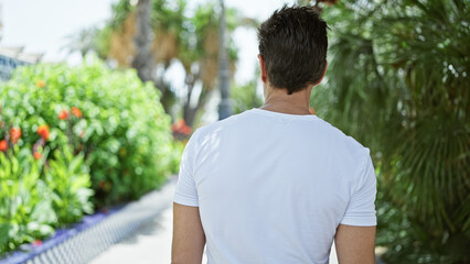 Young hispanic man standing backwards at park