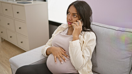 Emotional young pregnant woman, sitting at home on her sofa, talks and shares her doubts and ideas...
