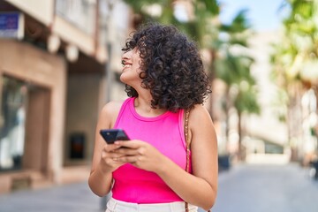 Young middle eastern woman smiling confident using smartphone at street