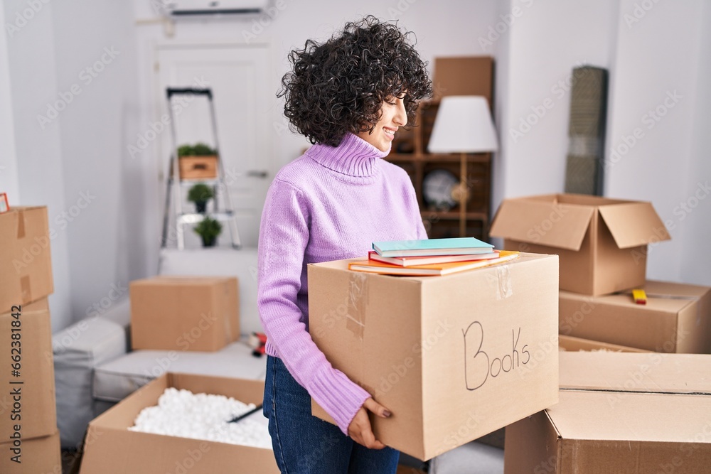 Canvas Prints Young middle east woman smiling confident holding books package at new home