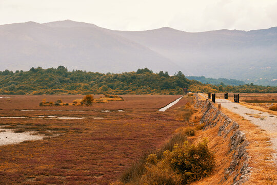 Autumn lonely road on the dam thru the lake and close to the mountains. Beautiful nature landscapes