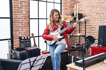 Fototapeta na wymiar Young woman musician playing electrical guitar at music studio