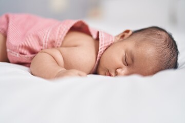 Adorable infant lying on bed sleeping at bedroom