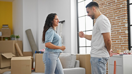 Man and woman couple playing rock scissors paper game smiling at new home