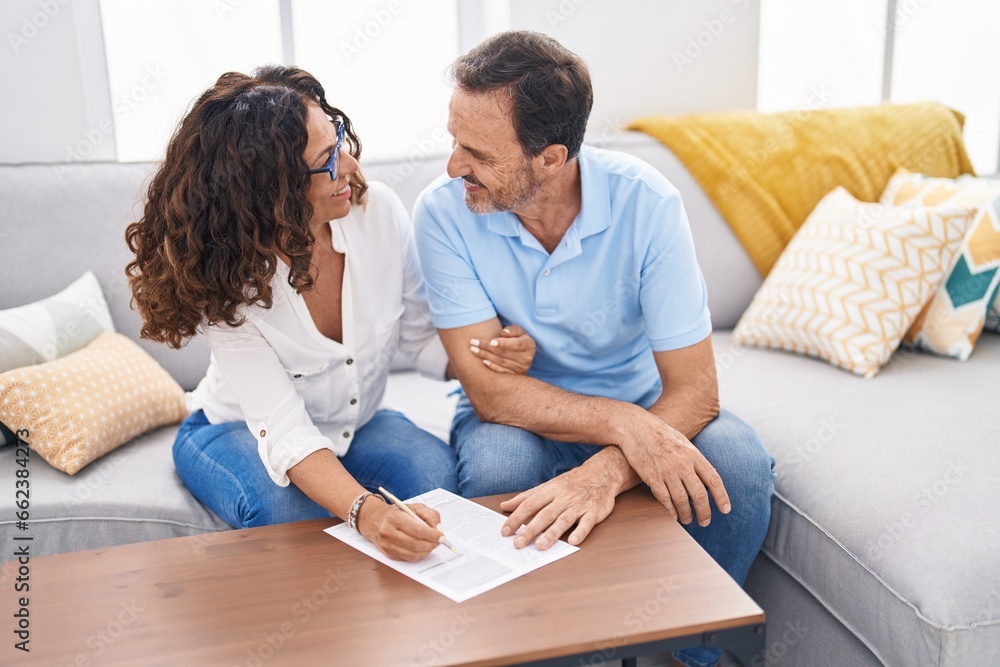 Sticker man and woman couple sitting on sofa writing on document at home