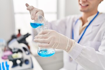 Young caucasian man scientist pouring liquid on test tube at laboratory