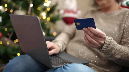 Middle age woman with grey hair doing christmas online shopping with laptop at home