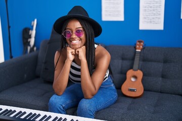 African american woman musician smiling confident sitting on sofa at music studio