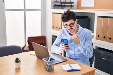Young caucasian man business worker using smartphone with winner expression at office