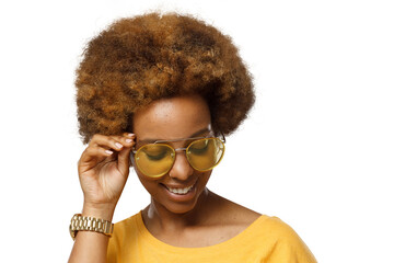 Smiling black woman wearing yellow sunglasses, touching her afro hair