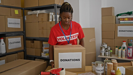 African american woman volunteer smiling confident holding donations package at office