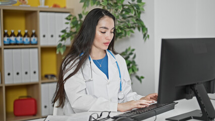 Young beautiful hispanic woman doctor using computer working at the clinic
