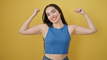 Fototapeta premium Young beautiful hispanic woman smiling confident doing strong gesture with arms over isolated yellow background
