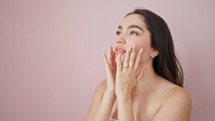 Young beautiful hispanic woman massaging face over isolated pink background