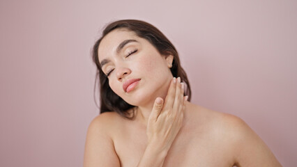 Young beautiful hispanic woman massaging neck over isolated pink background