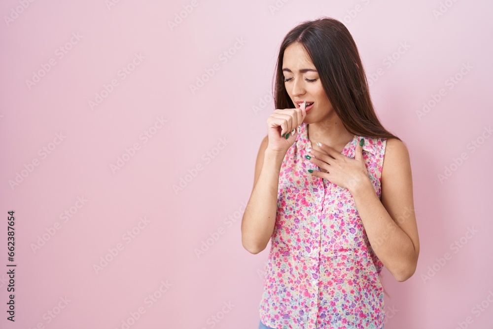 Poster young hispanic woman with long hair standing over pink background feeling unwell and coughing as sym