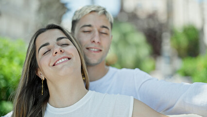 Naklejka premium Beautiful couple smiling confident breathing with arms open at park