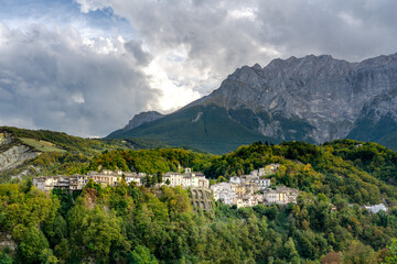 Quaint hillside village of Castelli in Abruzzo, nestled against majestic mountains. Sunlight bathes...