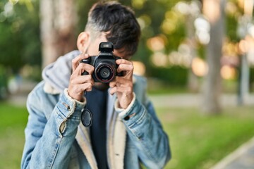 Young hispanic man using professional camera at park