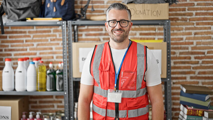 Grey-haired man volunteer smiling wearing vest at charity center