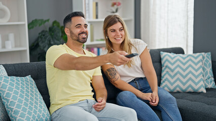 Obraz premium Man and woman couple sitting on sofa watching television at home