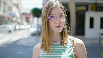 Young blonde woman standing with serious expression at street