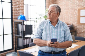 Middle age grey-haired man business worker smiling confident using smartphone at office