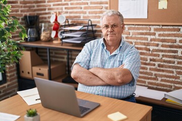 Middle age grey-haired man business worker smiling confident sitting with arms crossed gesture at office