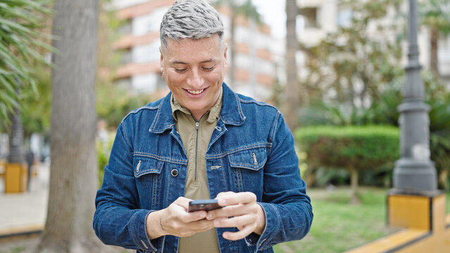 Young caucasian man using smartphone smiling at park