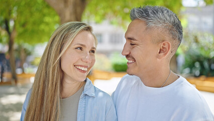 Fototapeta premium Man and woman couple looking each other standing together at park