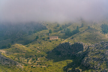 Scenic panoramic view of mountain landscapes, wooden mountain hut in the fog. Mallorca, Spain. Focus blurred due to fog.