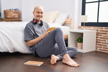 Young caucasian man using smartphone sitting on floor at bedroom