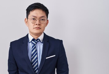 Young asian man wearing business suit and tie relaxed with serious expression on face. simple and natural looking at the camera.