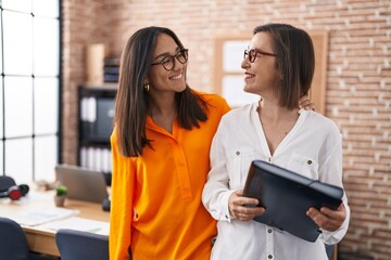 Two women business workers holding binder at office