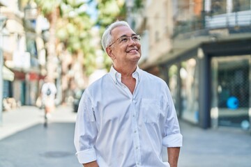 Middle age grey-haired man smiling confident looking to the sky at street