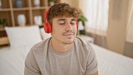 Young, handsome hispanic man relaxing in comfort, joyfully listening to fun music, sitting on a...