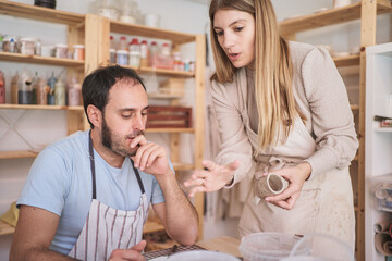 Potter woman helping her student in the ceramic workshop. Hobby and craft concept.