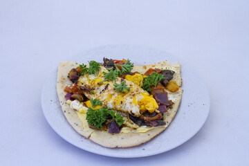 Fried egg and roasted vegetables on naan bread isolated on a plate on a clear background with copy space