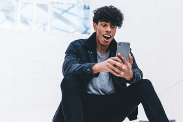 Surprised African American man using smartphone