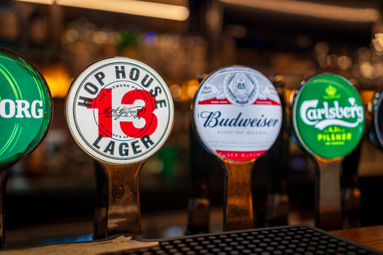 Bright label of HOP HOUSE 13 LAGER beer on a tap in a pub with bubbles in the background and other beer taps, to the right and left of it with logos Dublin, Ireland 03-26-2023