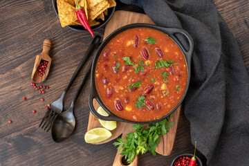 Bean and corn soup or ragout, red bean stew with corn chips nachos on a wooden background. Food...